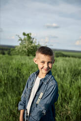 Smiling boy standing in field - ZEDF04539