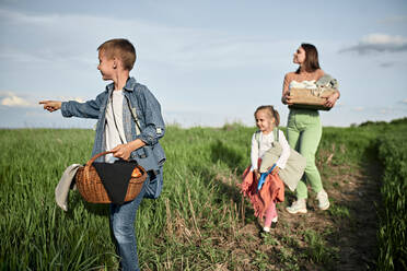 Junge mit Korb, der mit seiner Familie auf einem Feld spazieren geht - ZEDF04541