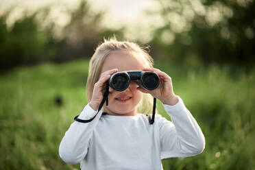 Girl looking through binoculars on weekend - ZEDF04554