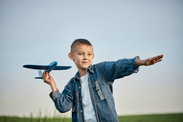 Junge hält Spielzeugflugzeug in einem Feld - ZEDF04567