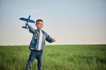 Boy playing with model on airplane in meadow - ZEDF04570