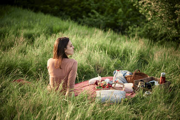 Contemplative woman sitting in field on weekend - ZEDF04589