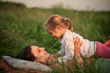 Lächelnde Mutter und Tochter liegen beim Picknick im Gras - ZEDF04621