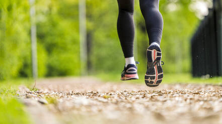 Junge Frau in Sportschuhen joggt im Park - STSF03209