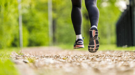 Young woman wearing sport shoes jogging in park - STSF03209