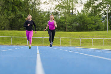 Junge Sportlerinnen beim Laufen auf dem Sportplatz - STSF03215