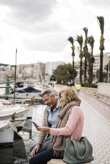 Älteres Paar, das am Hafen in der Stadt sitzt und ein Buch liest - JOSEF09598