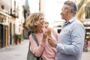 Happy mature couple having ice cream in city - JOSEF09607