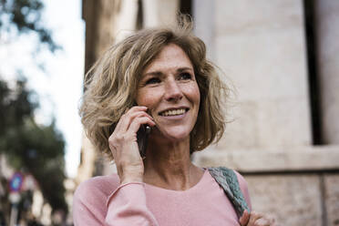 Lächelnde Frau, die mit einem Smartphone telefoniert - JOSEF09621