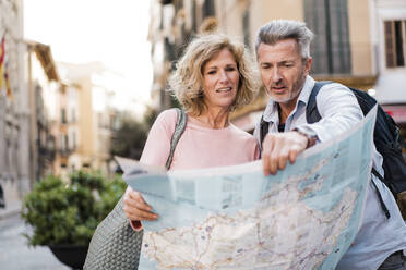 Mature man examining map with woman in city - JOSEF09627