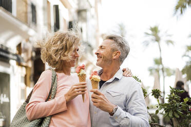 Happy mature couple having ice cream in city - JOSEF09658