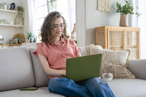 Glückliche Geschäftsfrau mit Brille, die zu Hause am Laptop arbeitet - VPIF06047