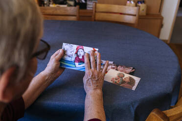 Ältere Frau mit Fotos der Familie zu Hause - IHF00794