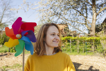 Happy woman with multi colored pinwheel toy at playground - IHF00814
