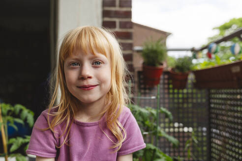 Smiling girl with red hair sitting on balcony - IHF00828