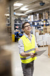 Smiling warehouse worker with tablet PC working in warehouse - PESF03792