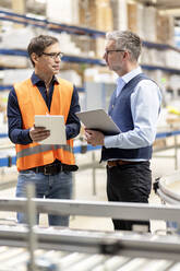 Worker with tablet PC discussing with manager in warehouse - PESF03835