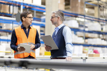 Worker and manager with tablet PC discussing together in warehouse - PESF03836