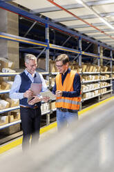 Happy worker and manager discussing over tablet PC in warehouse - PESF03848