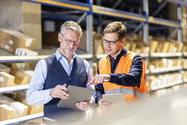 Worker pointing on tablet PC discussing with manager in warehouse - PESF03850