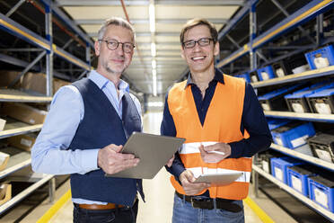 Smiling manager and worker standing together in aisle at warehouse - PESF03902