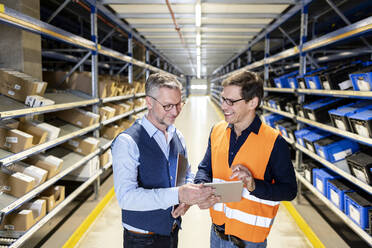 Smiling worker looking at manager discussing over tablet PC in warehouse - PESF03904