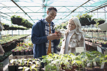 Happy couple shopping for potted plants at garden shop - CAIF32601