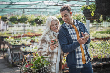 Ehepaar mit Smartphones beim Einkaufen im Gartengeschäft - CAIF32622