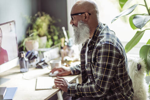 Senior man with beard using computer in home office - CAIF32628