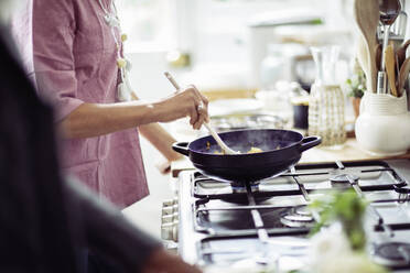 Woman cooking in wok on kitchen stove - CAIF32632