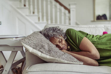 Serene senior woman napping on living room sofa - CAIF32648