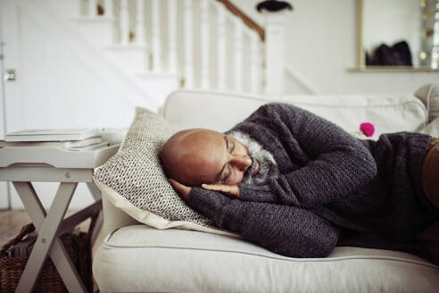 Müder reifer Mann schläft auf dem Wohnzimmersofa - CAIF32659