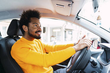 Lächelnder Afro-Mann mit gelbem T-Shirt fährt Auto - PNAF03859
