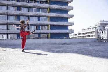 Happy woman kicking enjoying at parking deck - UUF26179