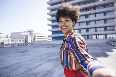 Glückliche Frau mit Afrofrisur, die sich auf einem Parkdeck amüsiert - UUF26182