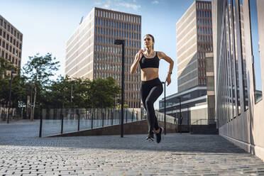 Junge Frau joggt auf einem Fußweg in der Stadt - JSRF02019