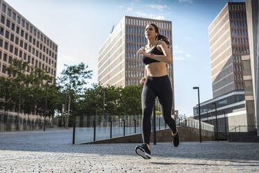 Junge Frau joggt in der Stadt an einem sonnigen Tag - JSRF02020