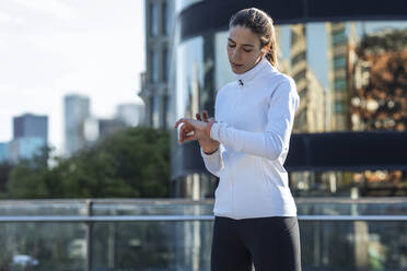 Young woman checking time in smart watch - JSRF02023