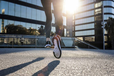 Young woman running on footpath in city - JSRF02026