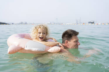 Glückliches Mädchen mit Vater beim Schwimmen im Meer - SVKF00176