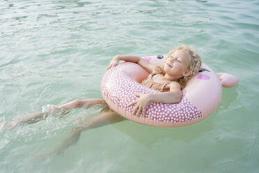 Girl with inflatable ring floating on sea - SVKF00179