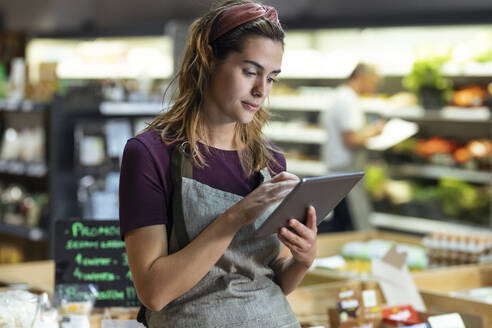 Ladenbesitzer mit Tablet-PC im Biomarkt - JSRF02046