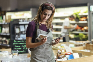 Shop owner holding tablet PC analyzing product at organic market - JSRF02047