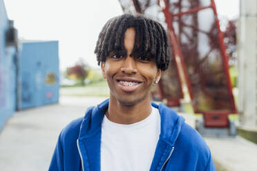 Happy young man with locs wearing dental braces - MEUF05654