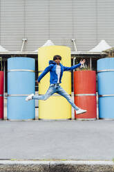 Happy young man jumping in front of concrete pipes - MEUF05698