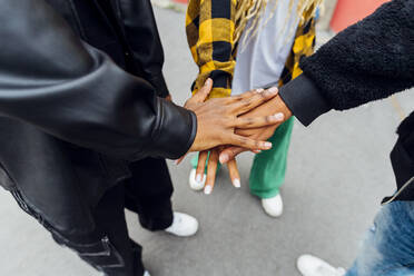 Friends stacking hands standing on footpath - MEUF05731