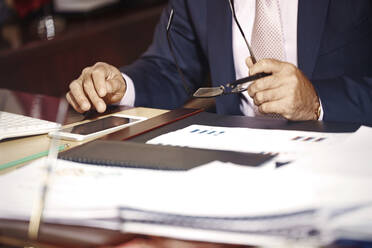 Geschäftsmann mit Brille bei der Arbeit am Smartphone im Büro - AZF00408