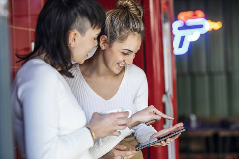 Lächelnde Restaurantbesitzer, die über Tablet-PCs diskutieren - JSRF02067