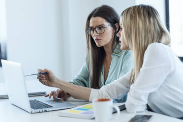 Businesswomen discussing over laptop at desk in office - JSRF02073