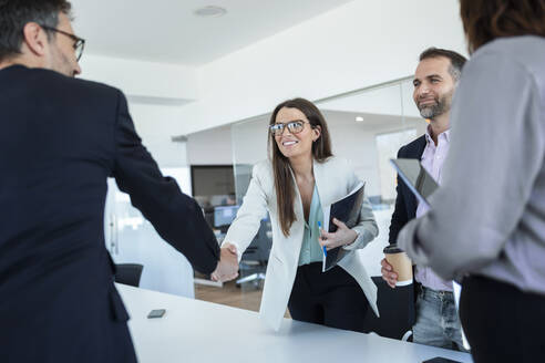 Geschäftsfrau beim Händeschütteln mit einem Kollegen im Büro - JSRF02097